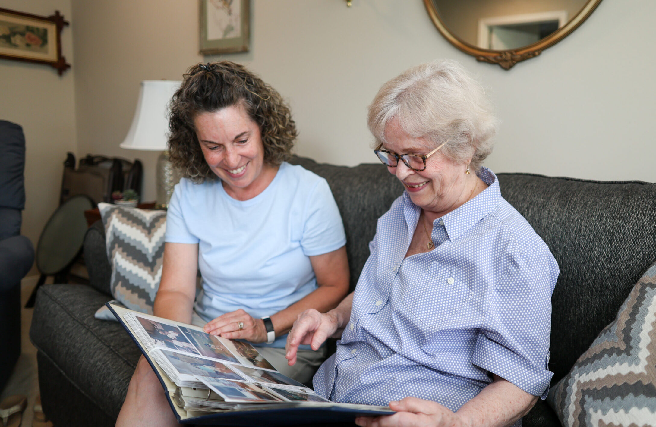 Senior and adult child looking at photo album together at home.