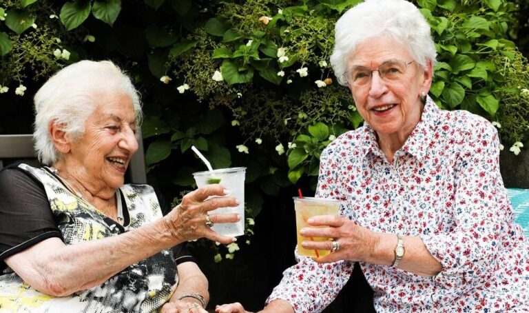 Two senior women drinking outdoors