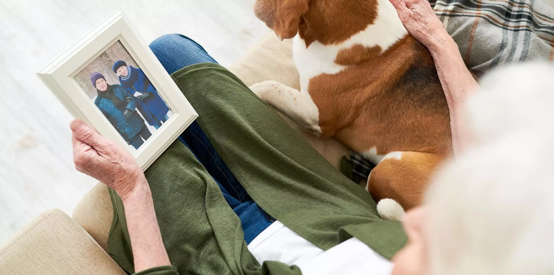 Senior woman petting dog while looking at photo