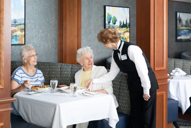 Server bringing dish to senior women
