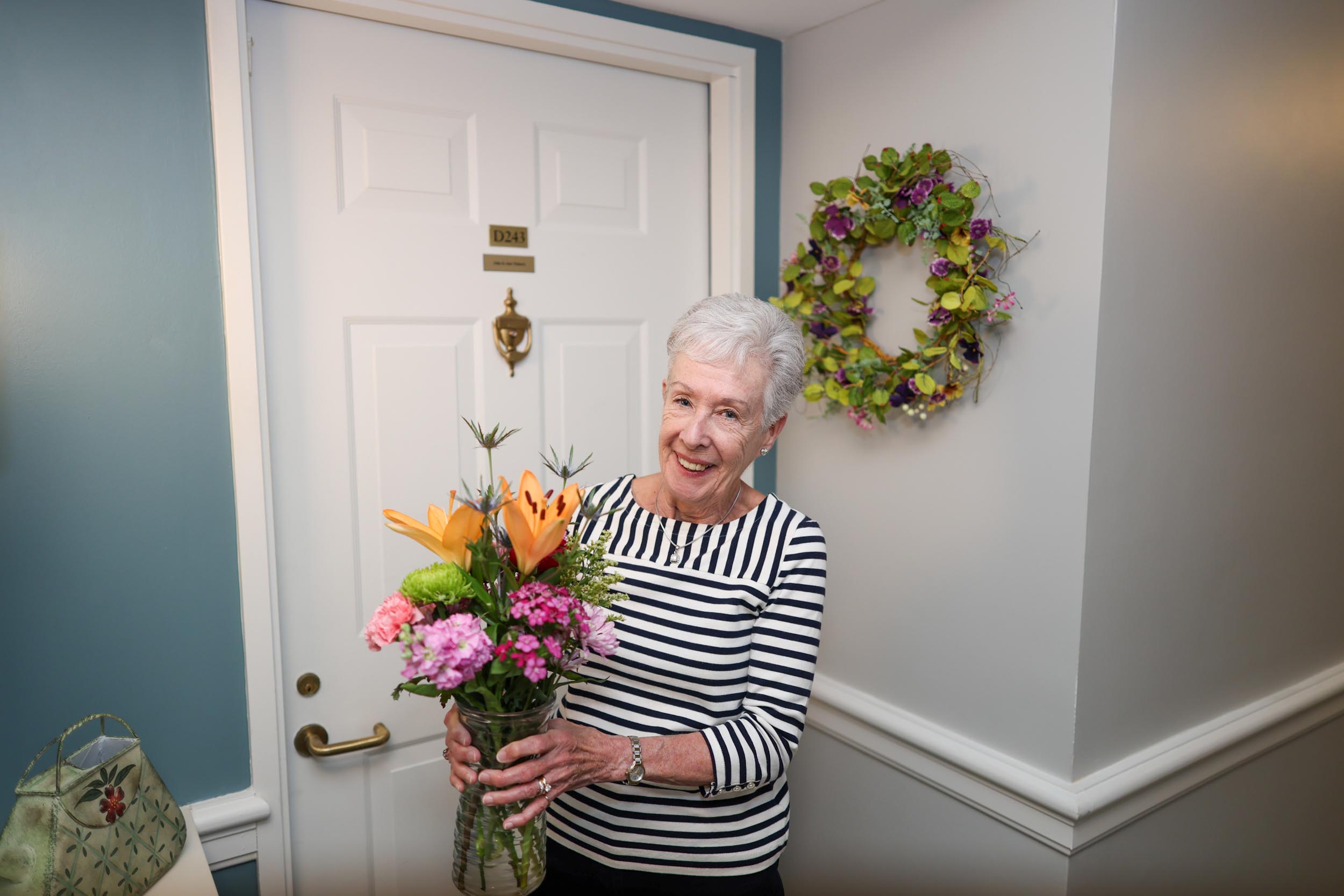 Resident Jean with flowers outside of her apartment home