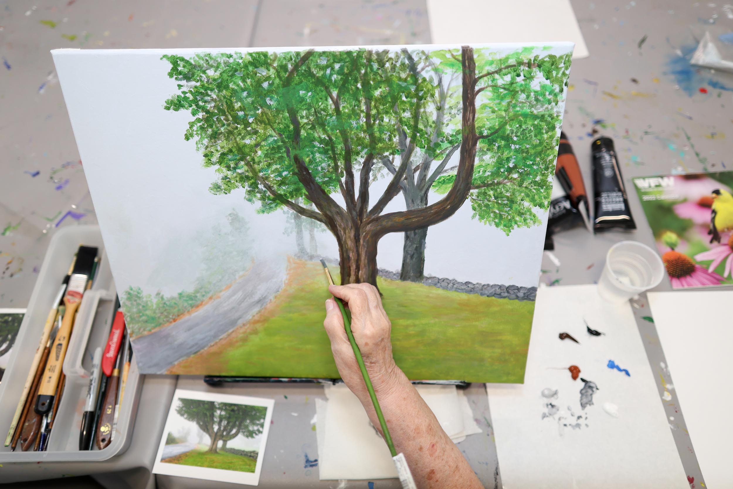 Resident painting a tree on a canvas