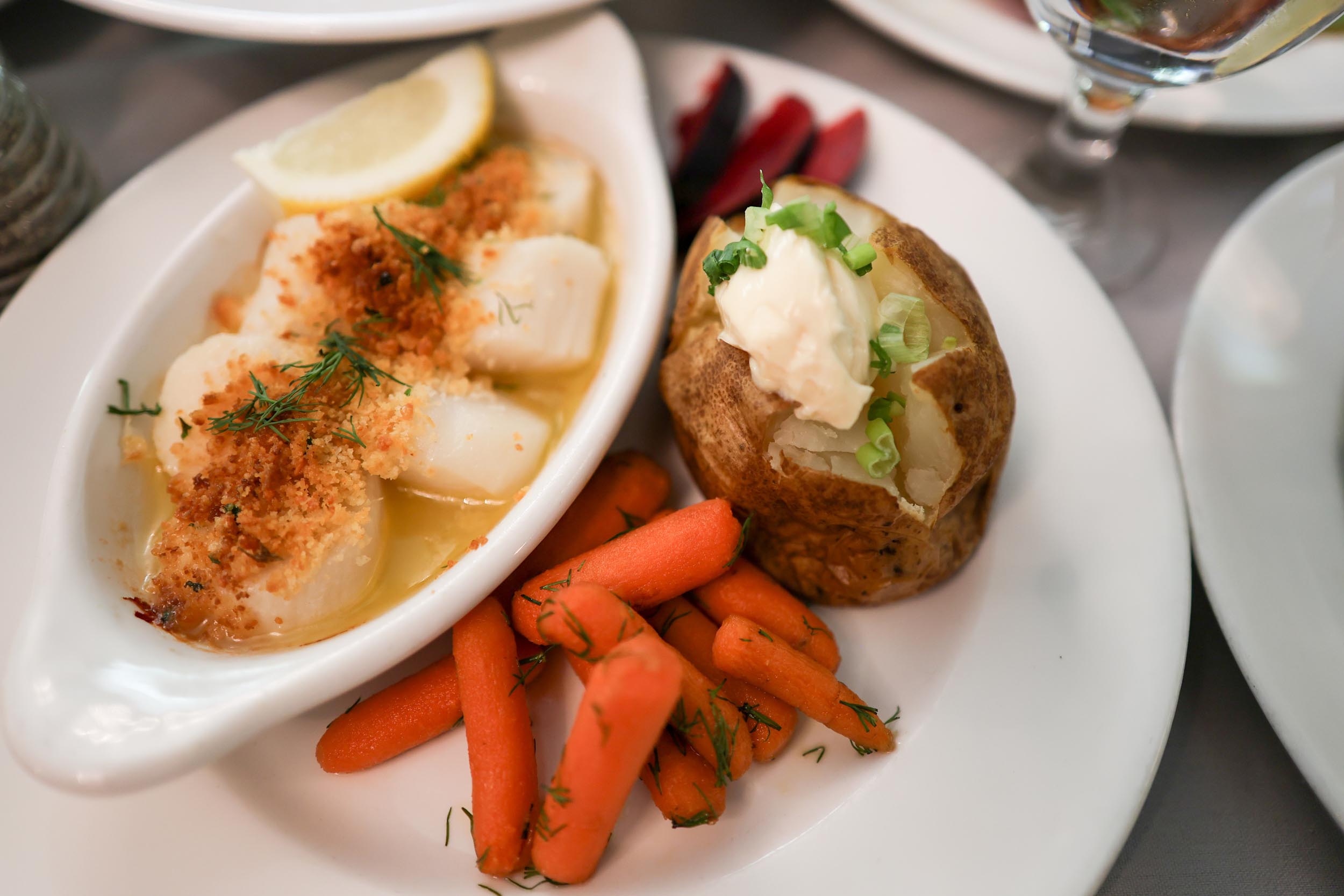 Plated meal of scallops, baked potato and carrots