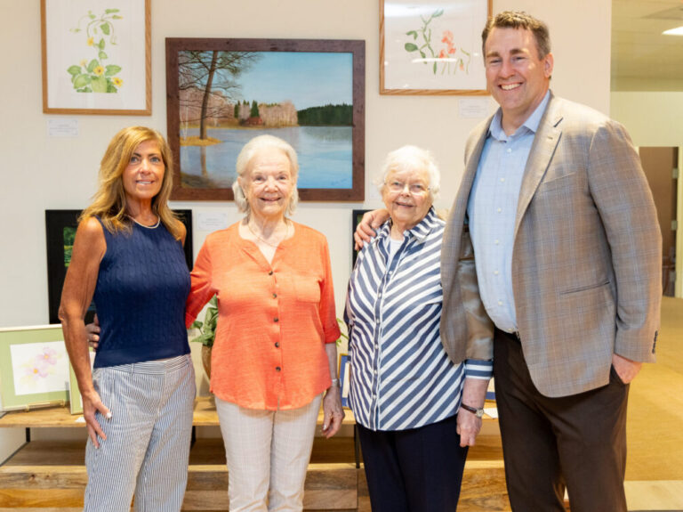 New Pond Village Activities Director Carolyn Roycroft, residents Celeste Hurley and Gunilla Knuston and Campus Executive Director Adam Manchester at the recent unveiling of resident artwork in Benchmark Senior Living’s corporate offices.