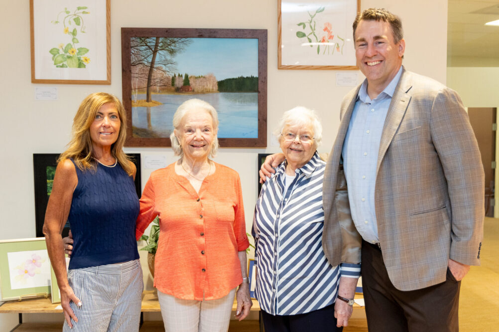 New Pond Village Activities Director Carolyn Roycroft, residents Celeste Hurley and Gunilla Knuston and Campus Executive Director Adam Manchester at the recent unveiling of resident artwork in Benchmark Senior Living’s corporate offices.