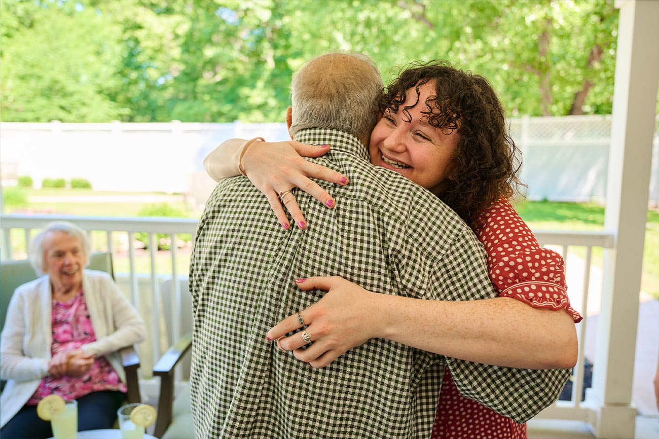 Memory care resident and associate hugging