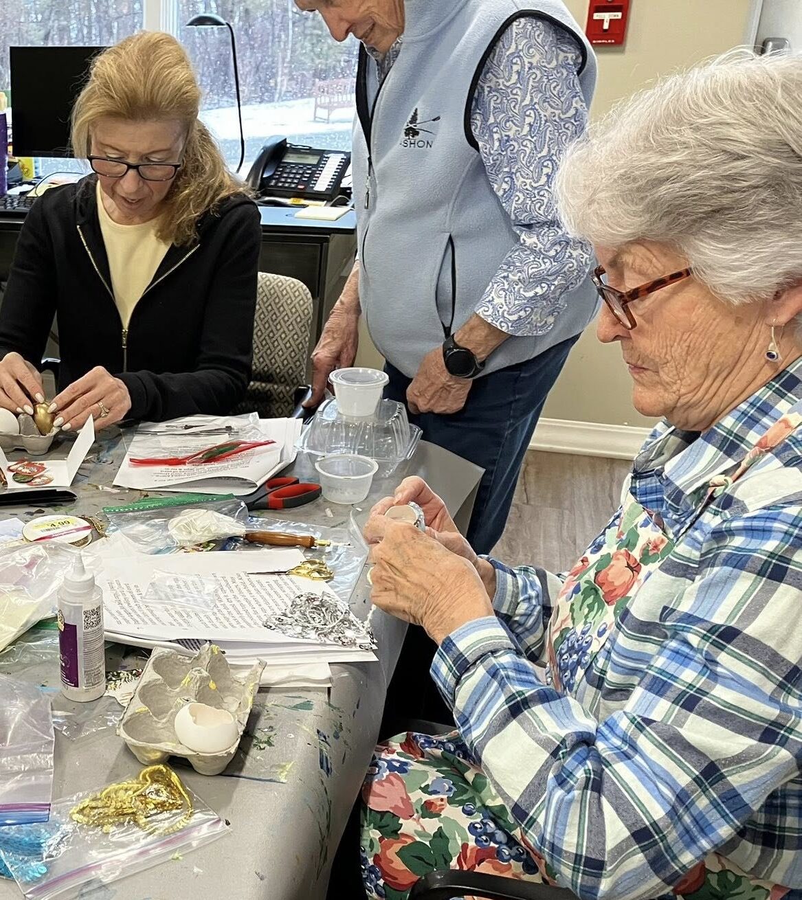 Stephie Peck and fellow New Pond Village residents crafting and decorating decoupage eggs during a creative class led by resident instructor Jean Huff in the craft room.